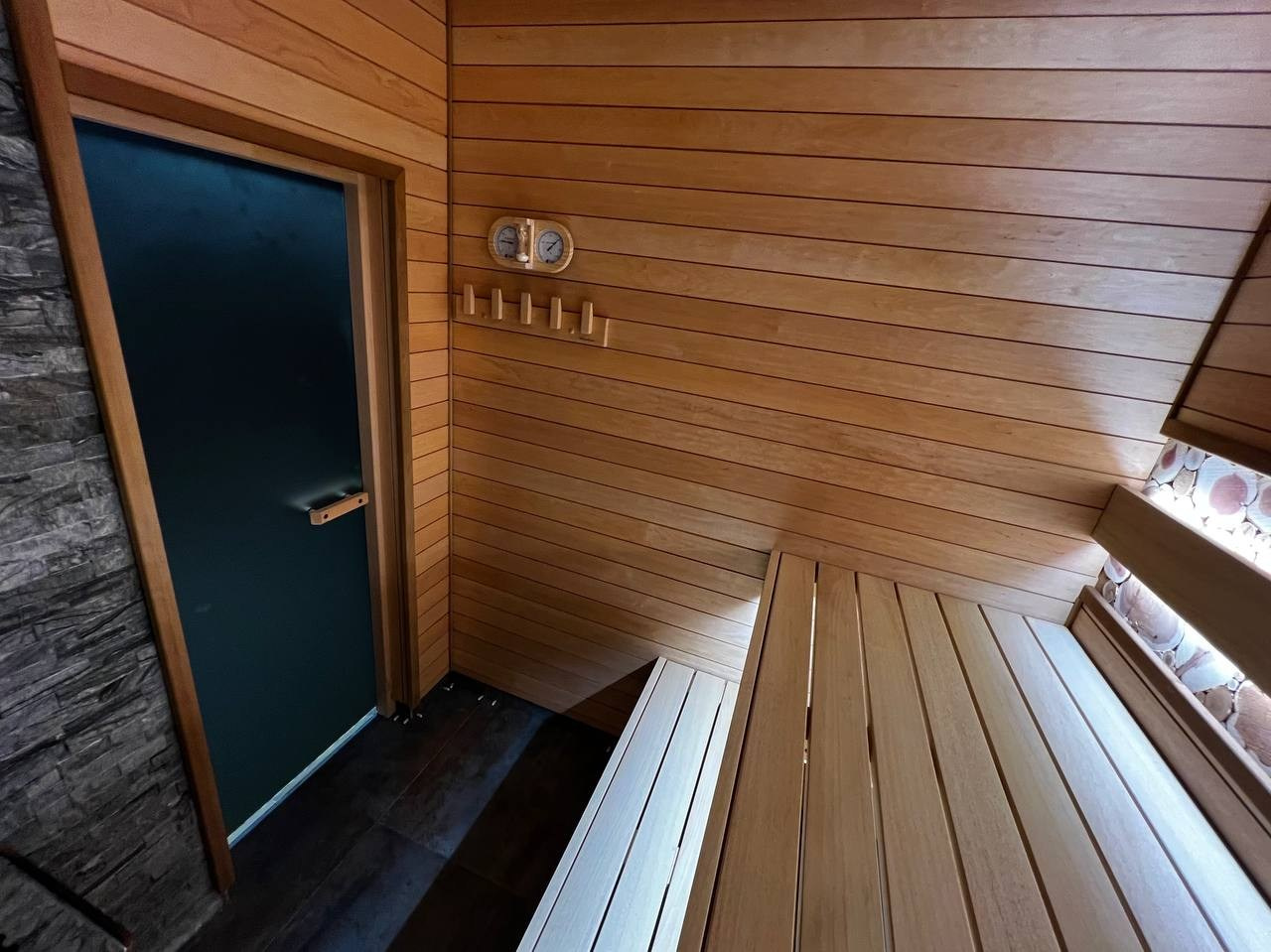 Компактная баня в Терра-Выборгском: светлая ольха в горизонтали и абаш на парящих полках визуально расширяют пространство. SaunaTopMasters