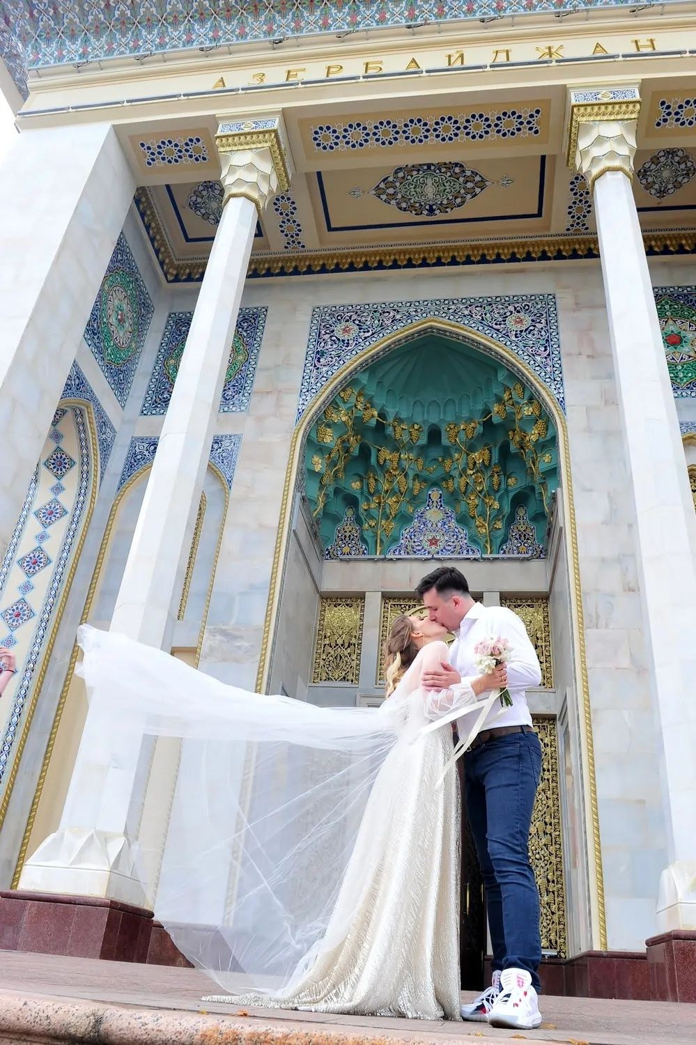 Свадьба на ВДНХ, молодожены обнимаются, фото жениха и невесты в полный рост, фата невесты развевается, красивый павильон на ВДНХ