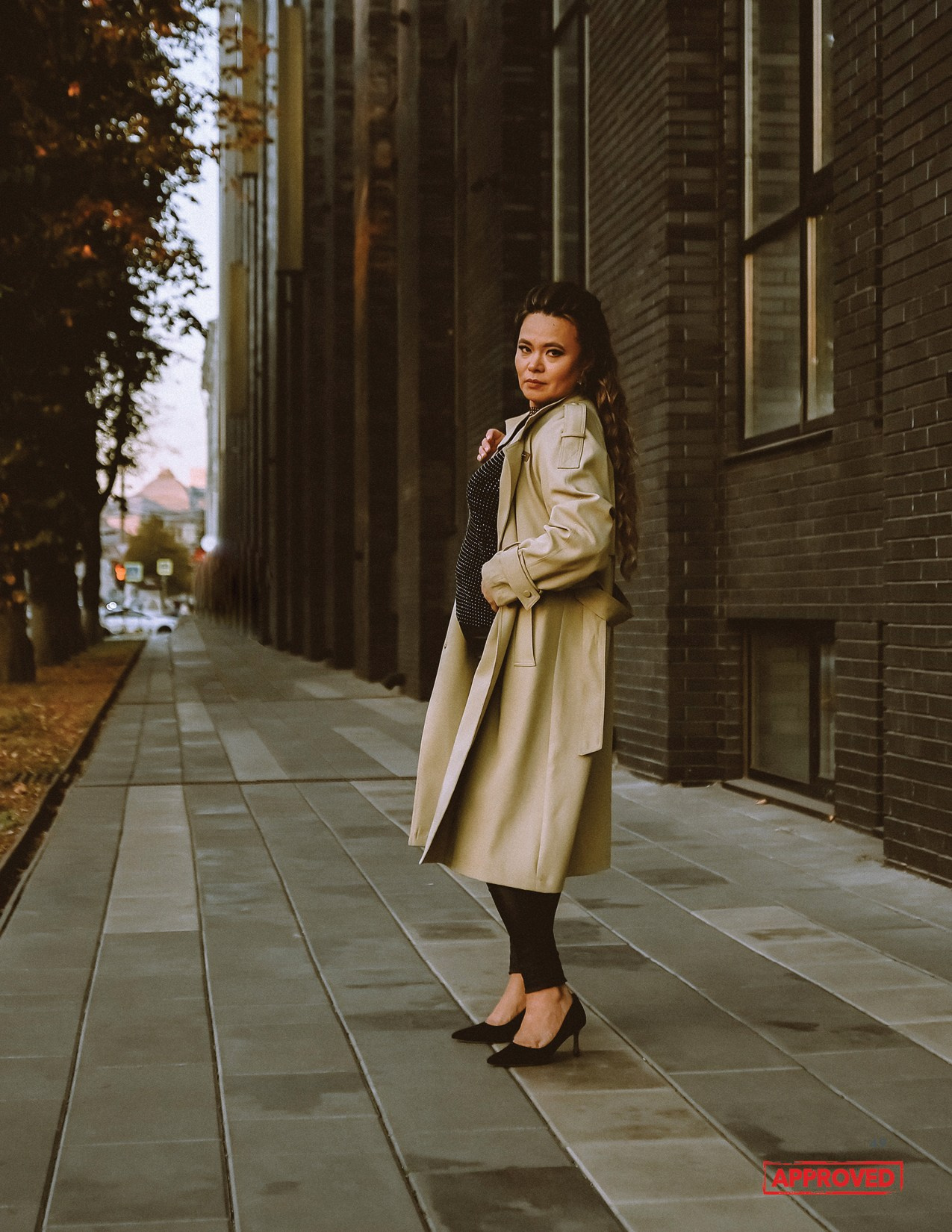 На фото девушка идет вдоль здания.