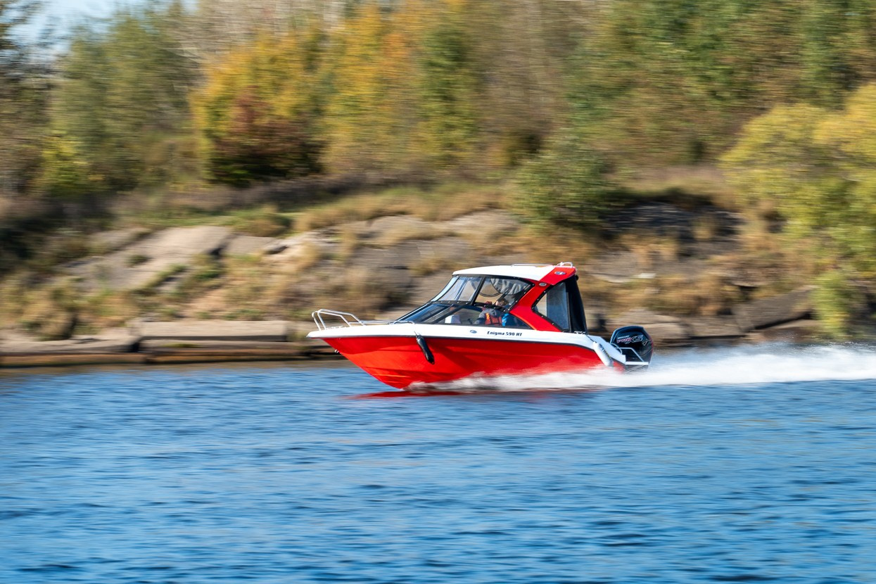 Вид издали на катер Enigma, движущийся по водной глади