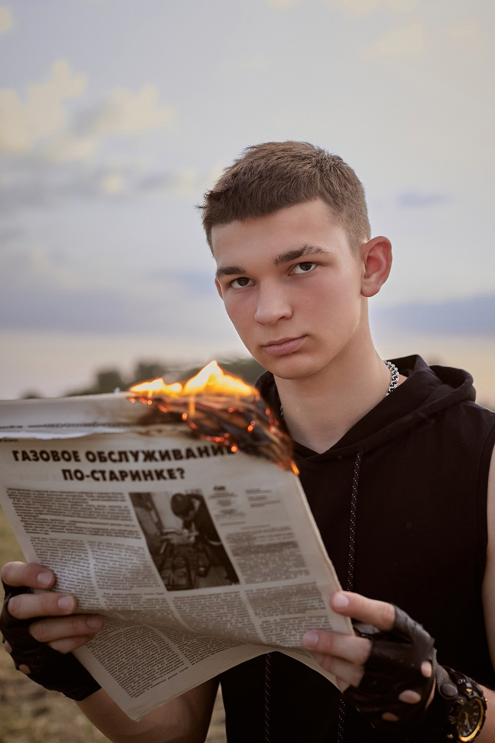 Фотограф в Москве. Креативное фото. Парень с горящей газетой сидит на стуле в поле на закате.