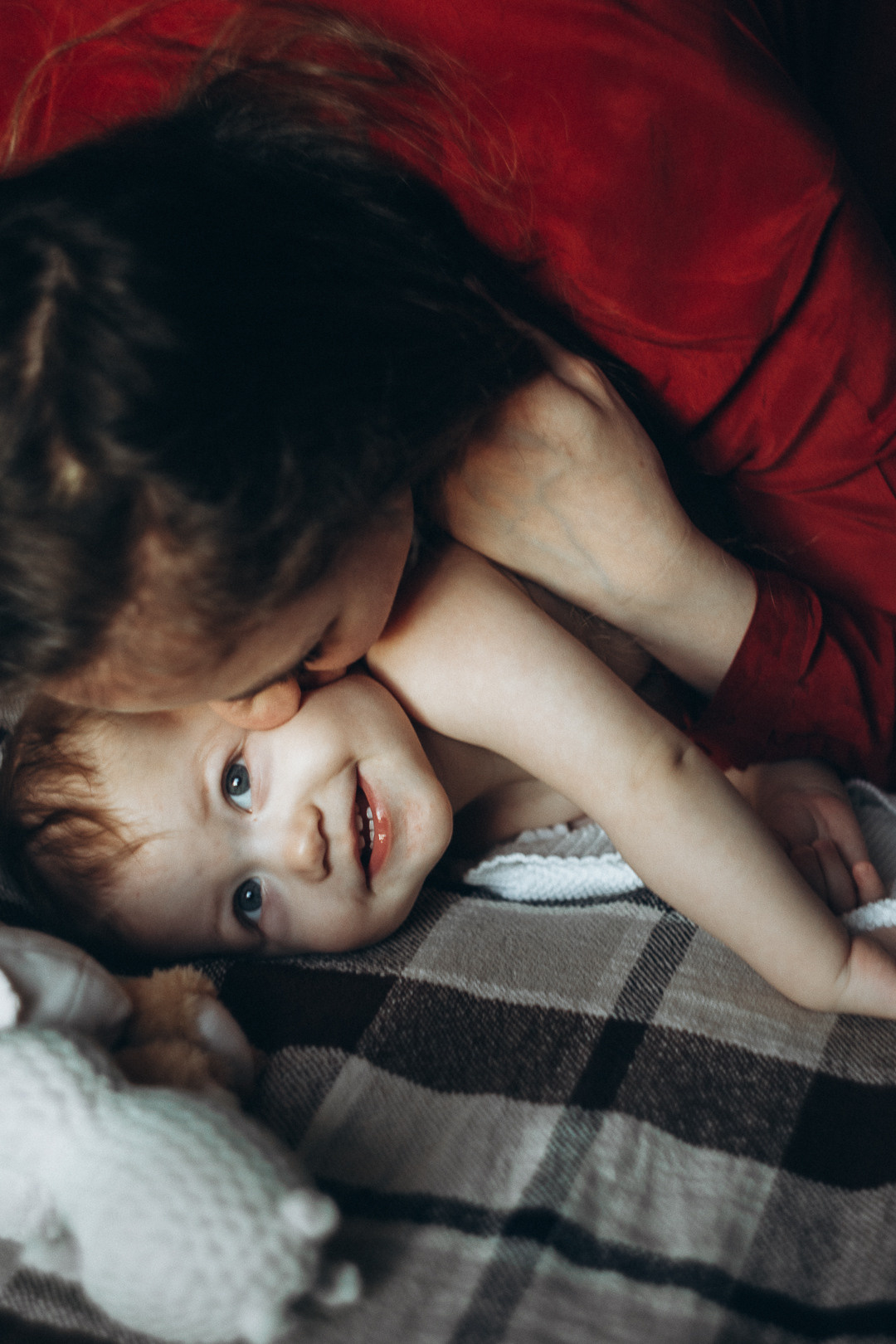 мама целует малышку на диване