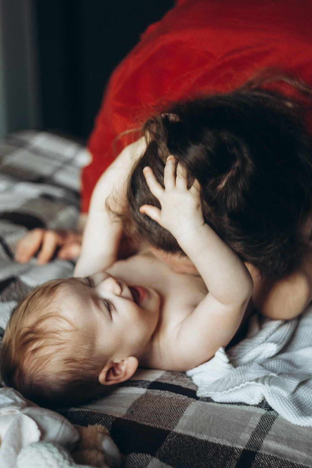 мама целует малышку в пузико на диване