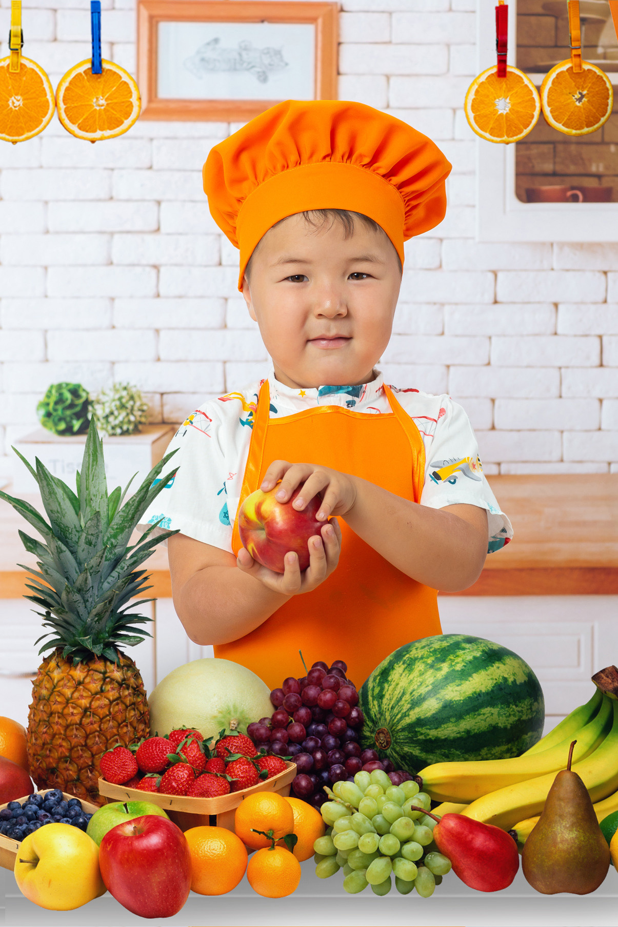 Детская тематическая костюмированная фотосессия на кухне. Поварята. Мальчик в костюме повара и фрукты.