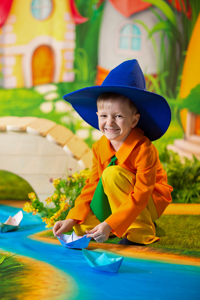 Детская тематическая костюмированная фотосессия, Маленькая страна Весна. Мальчик в костюме НезнайкИ запускает бумажный кораблик.