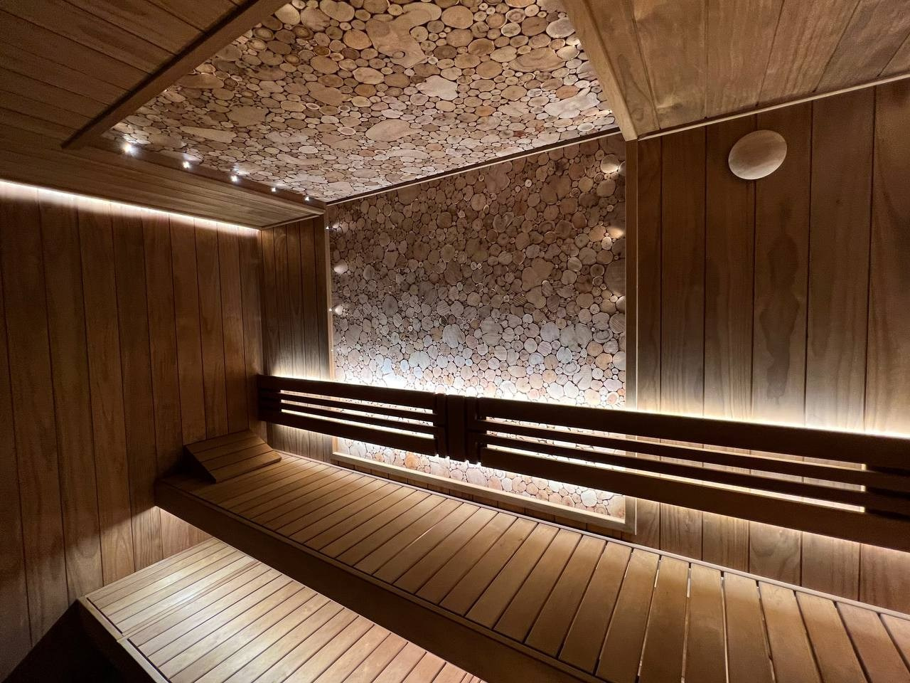 Парная в Небе. Полностью выполнена из термоольхи с интеграцией массивных можжевеловых панно, оптоволокна и подвижных элементов полков. SaunaTopMasters