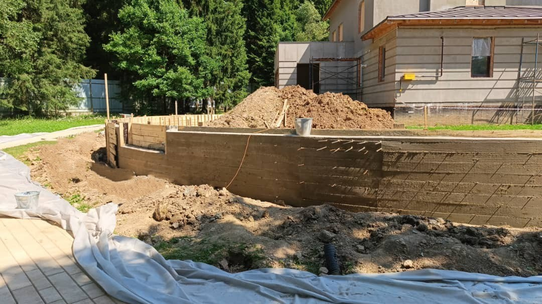 Заливка подпорной стенки из бетона — укрепление склона участка.