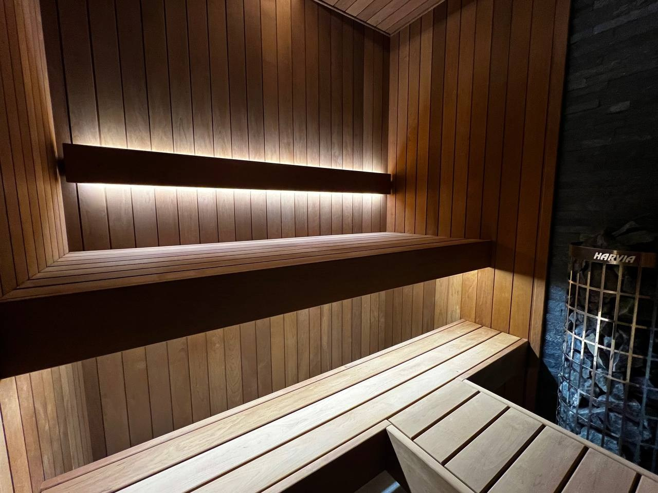 Компактная сауна в Охта Парке с электрокаменкой Harvia Cilindro, отделкой из термоольхи и сияющим можжевеловым панно. SaunaTopMasters