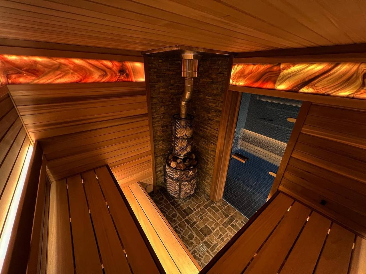 Баня в Сестрорецке, выполненная из кедра и абаша с ониксом, играющим цветом, создаёт тёплую и уютную атмосферу парения. SaunaTopMasters