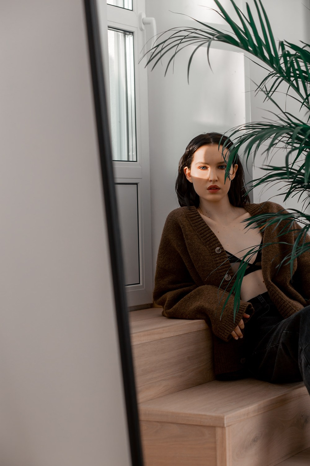 Девушка дома прилегла на ступеньки с растением