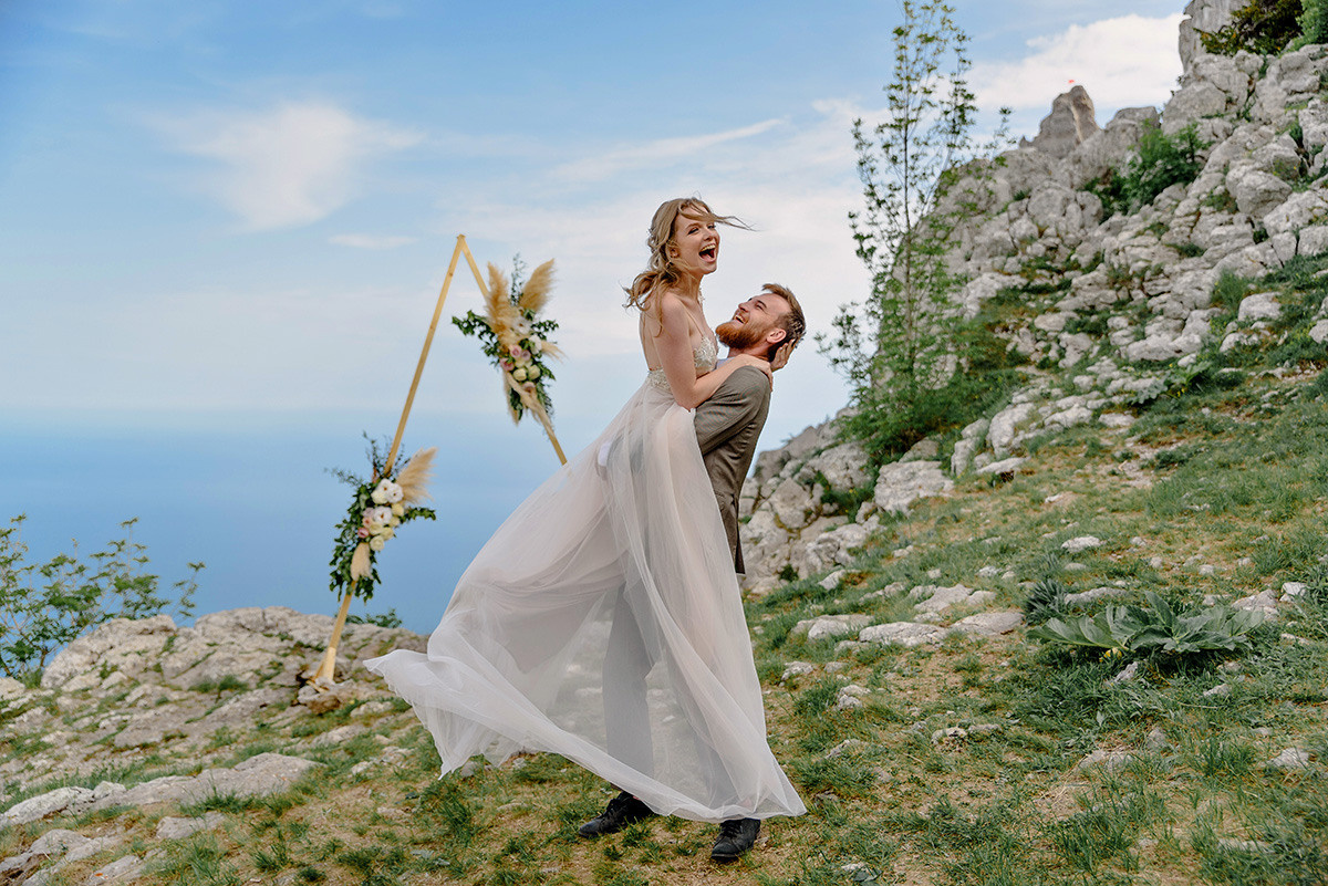 Жених поднял невесту на руки у арки на выездной регистрации.