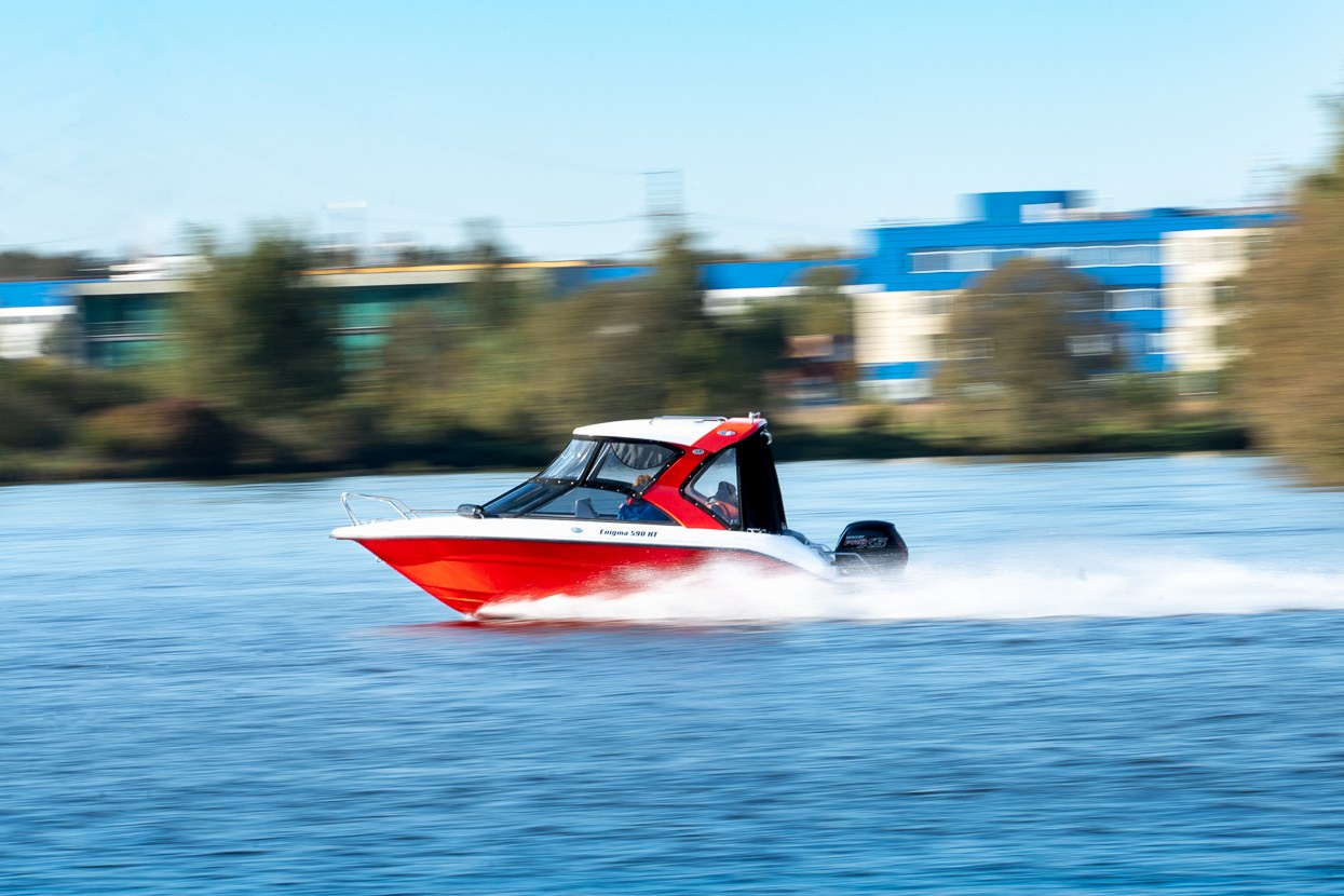 Крупный план лодки Enigma на ходу, водный след позади