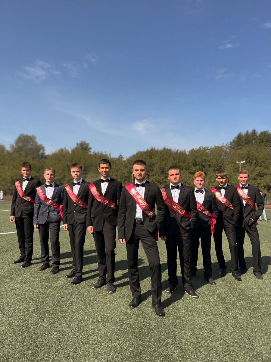 Парни - выпускники в строгих костюмах с лентами