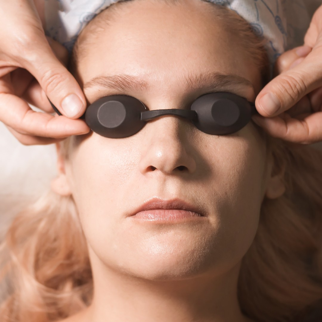 Черные очки для проведения эпиляции на лице. Женское лицо крупным планом