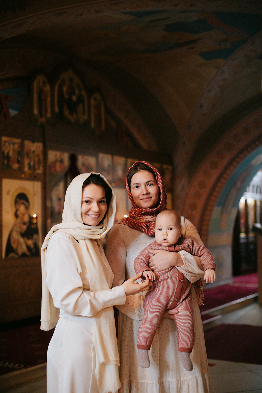 крёстная и мама с ребенком в храме на крещении