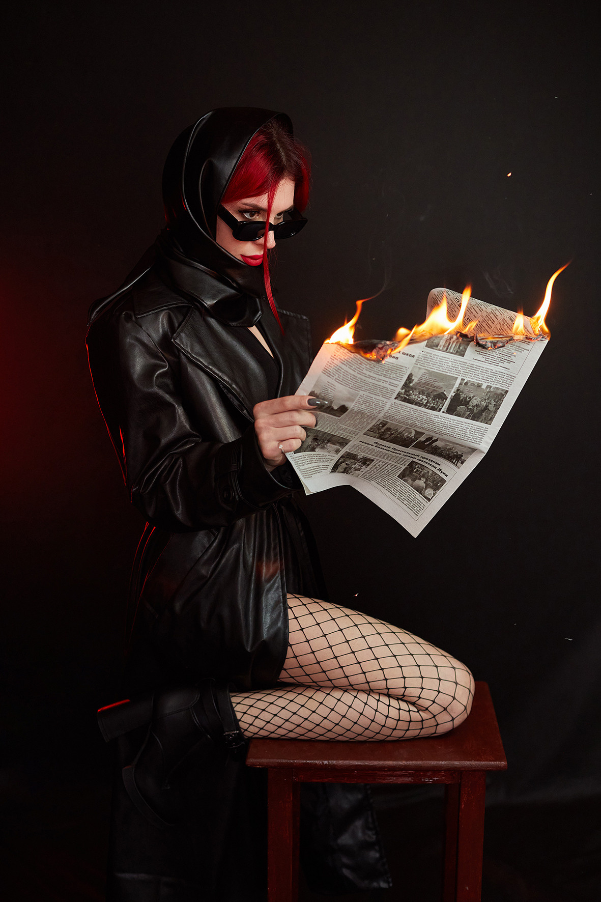 Девушка в кожаном плаще с красными губами читает горящую газету. Фотограф. Тимашевск. Кубань. Краснодарский край. Москва. Фотограф в Москве.