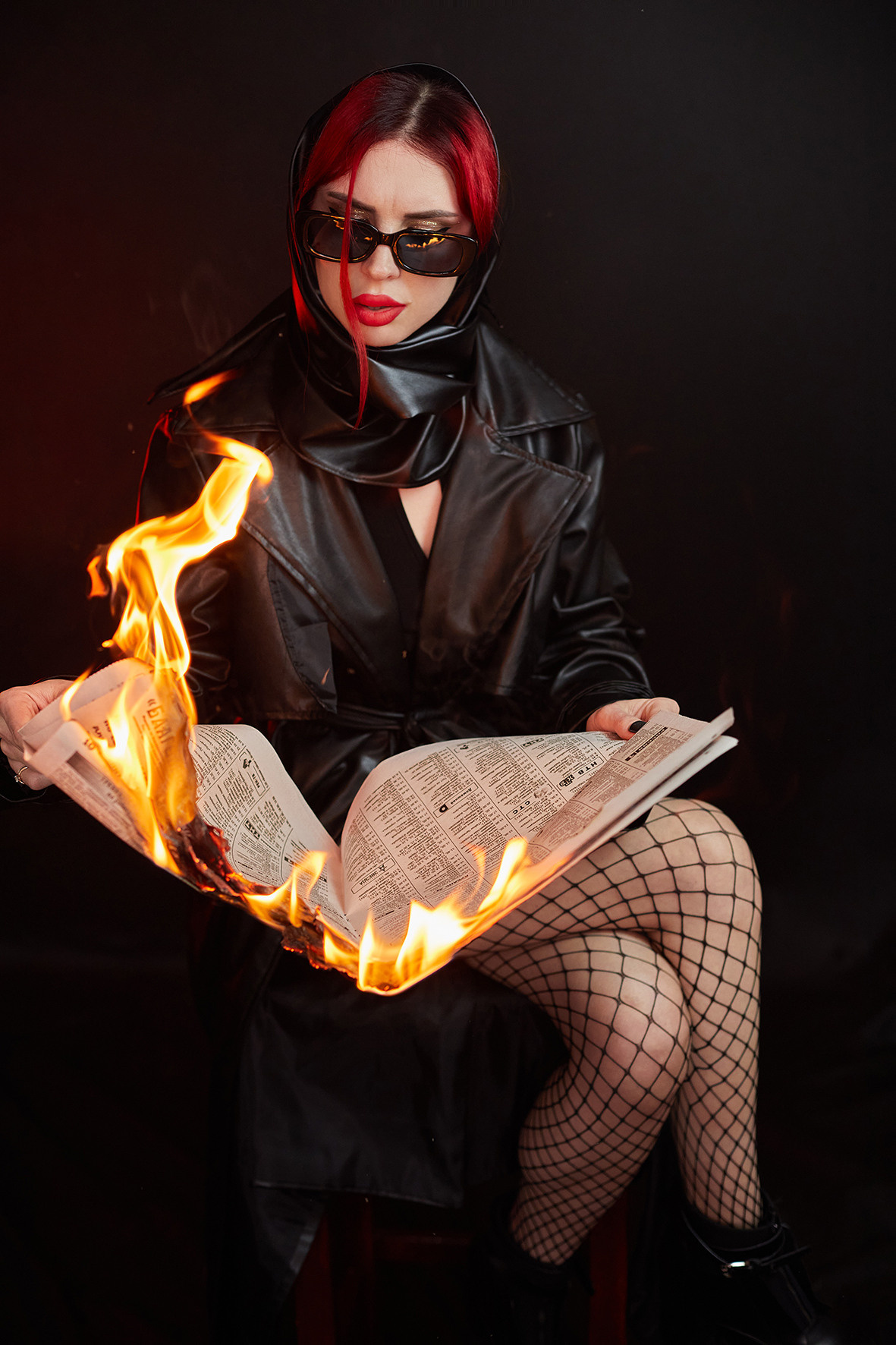 Девушка в кожаном плаще с красными губами читает горящую газету. Фотограф. Тимашевск. Кубань. Краснодарский край. Москва. Фотограф в Москве.