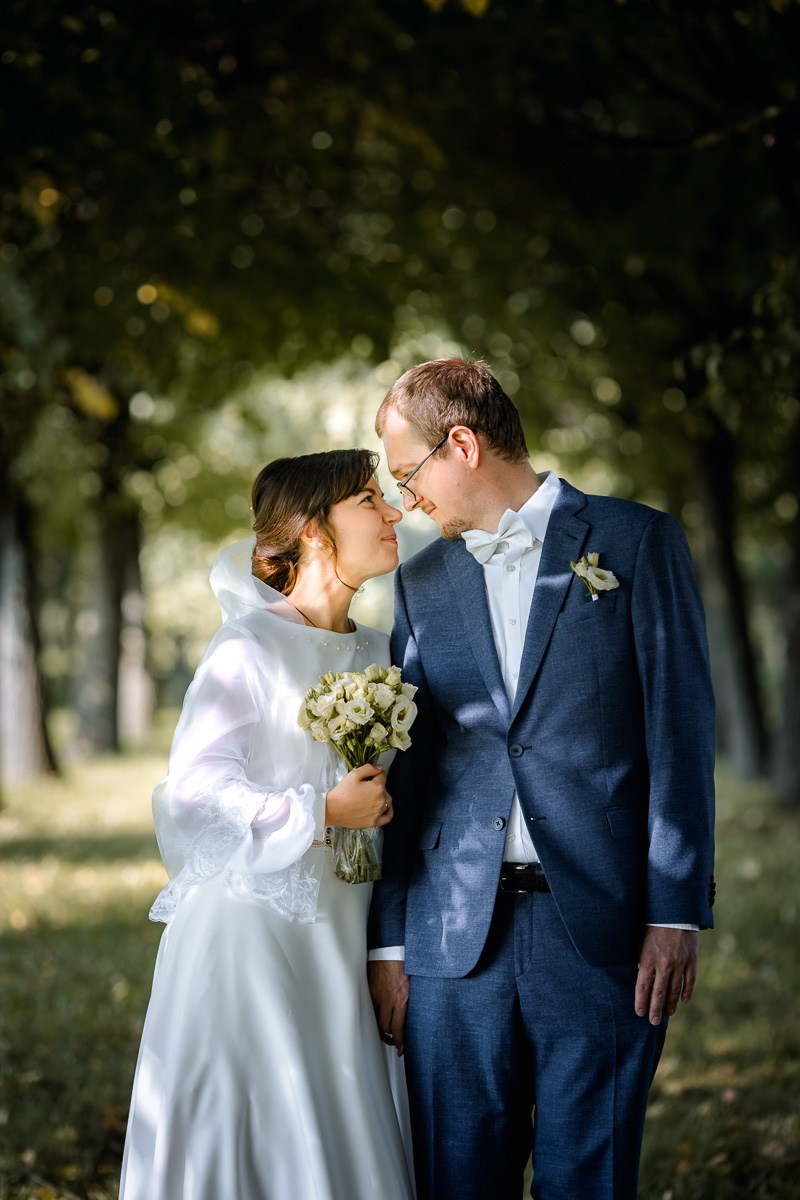 Жених и невеста смотрят друг на друга на аллее парка ЗАГСа Красносельского района СПб, средний план.