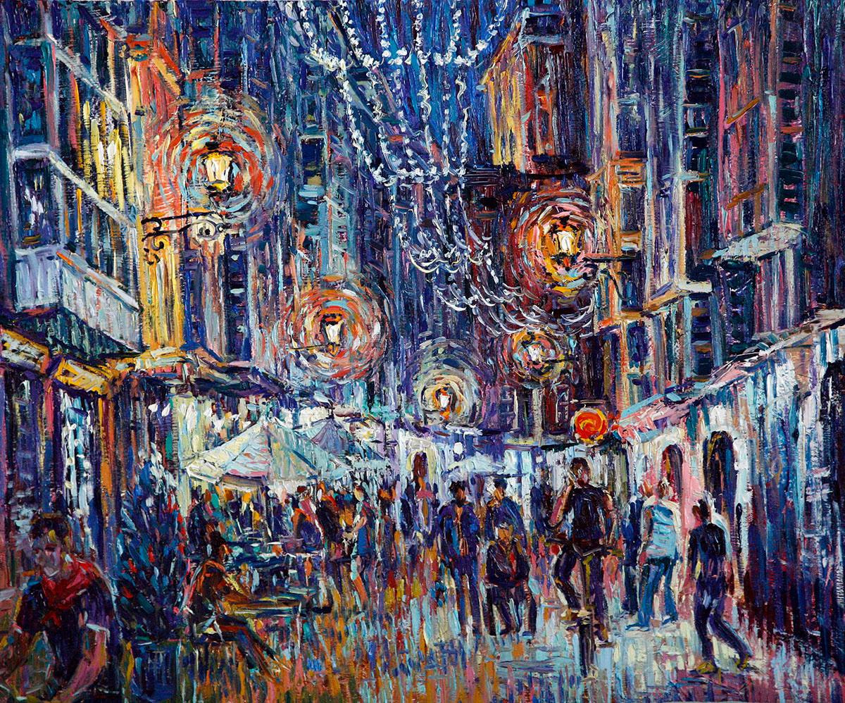 Street of bars with festive lighting and crowds of people.