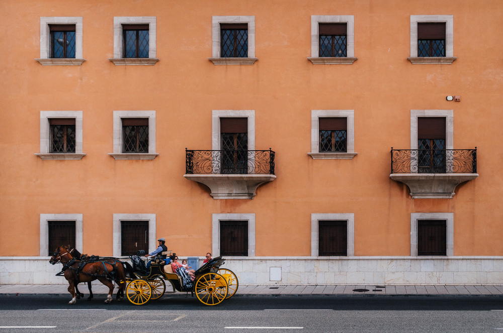 Palma, Mallorca island, Spain. Horse-drawn carriage in front of texture of multistorey apartment house wall with balconies and windows.