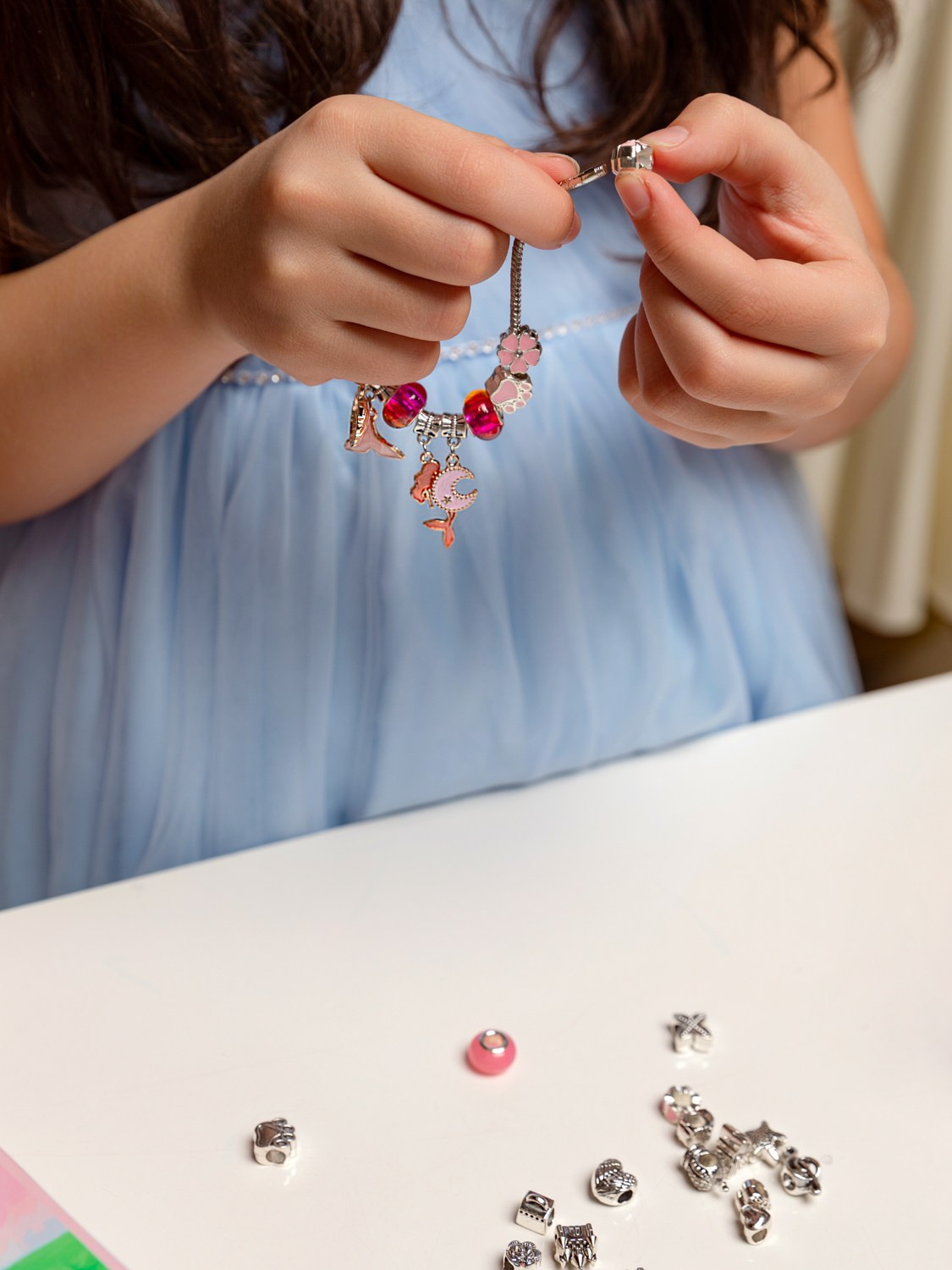 На фото девочка нанизывает на нить бусины.