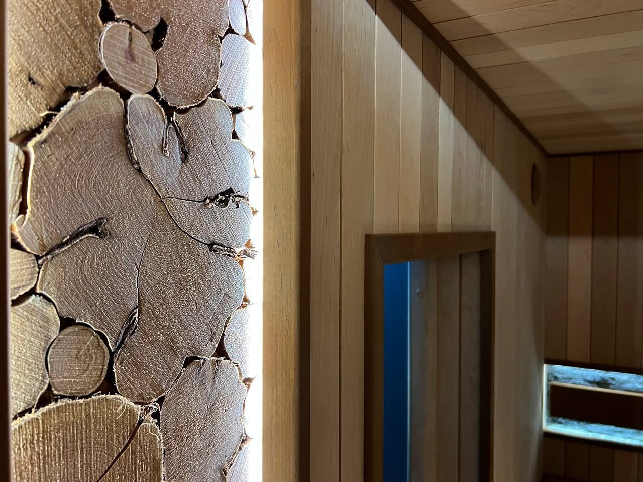 Просторная сауна в Сертолово из термоольхи с интеграцией можжевеловых линий и большого количества натурального камня. SaunaTopMasters