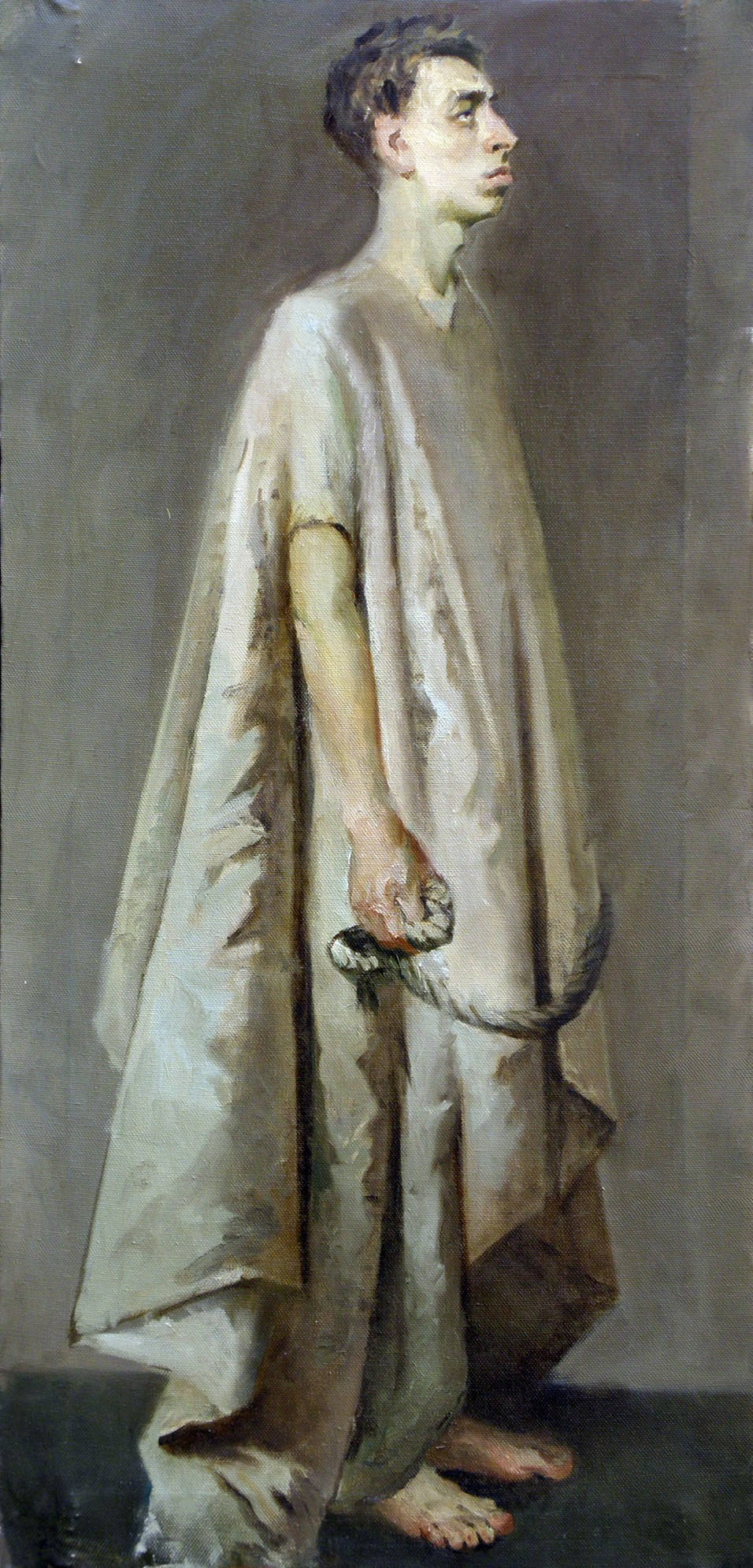 Молодой человек стоит в холщовой накидке и смотрит перед собой