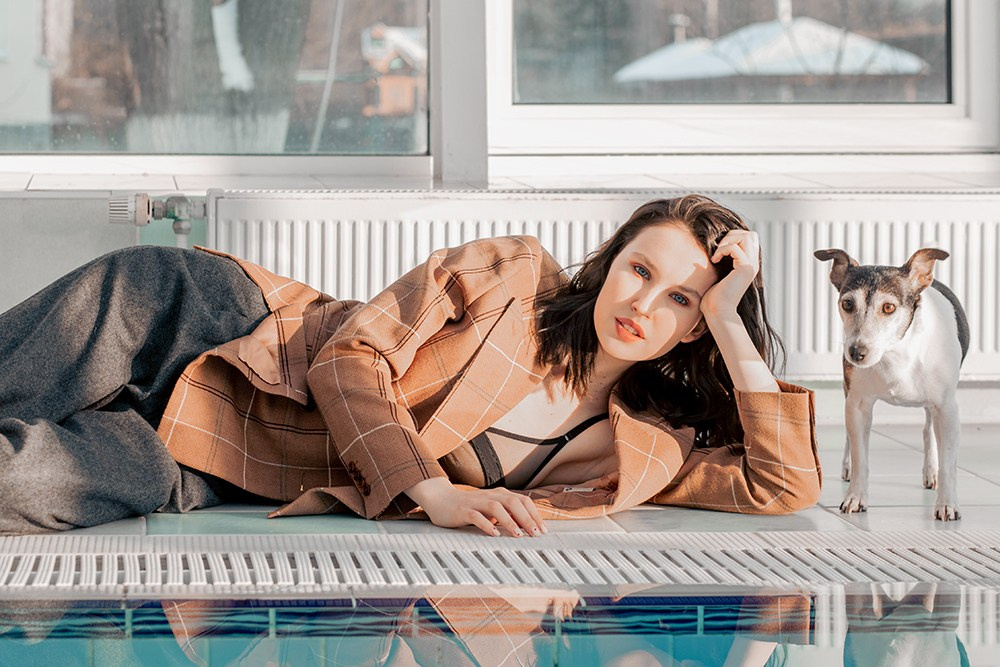 Девушка лежит в пиджаке у бассейна