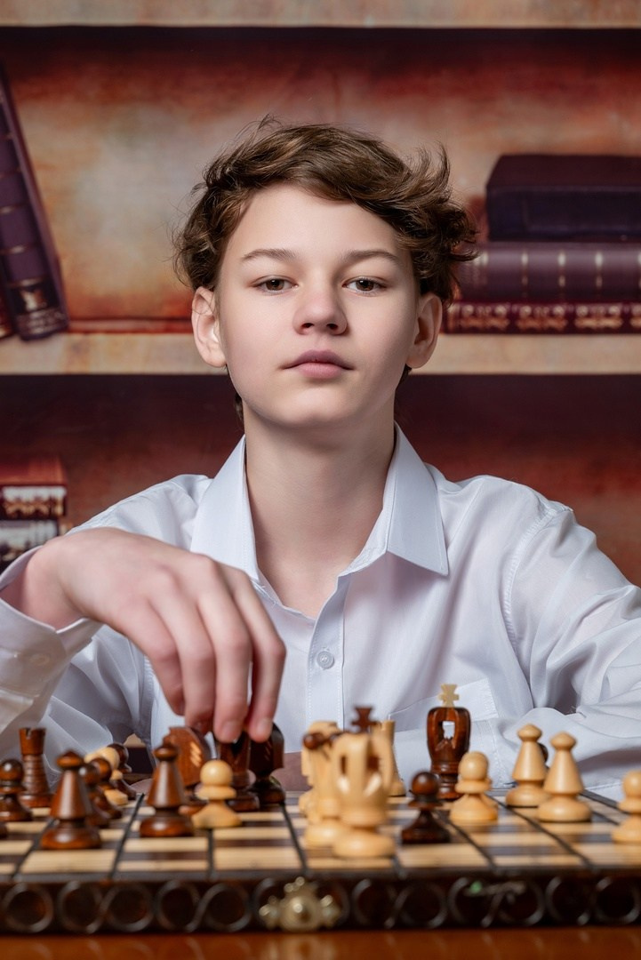 Юный шахматист играет в классе позируя школьному фотографу.
