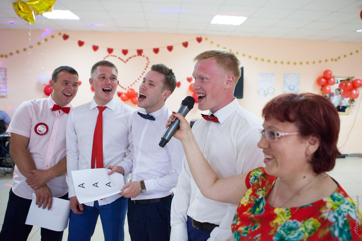 Яркая группа гостей смеются во время активного свадебного конкурса 