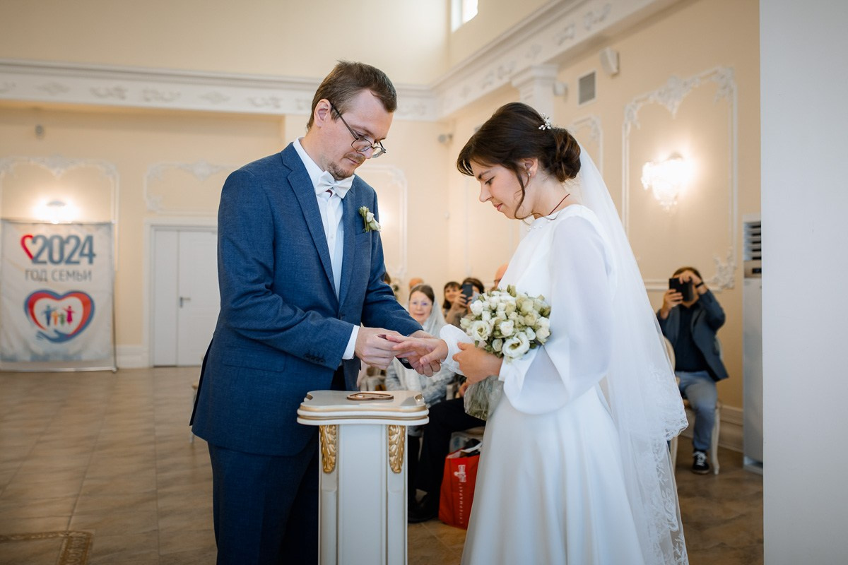 Жених и невеста в зале регистраций ЗАГСа Красносельского района Санкт-Петербурга ставят подписи