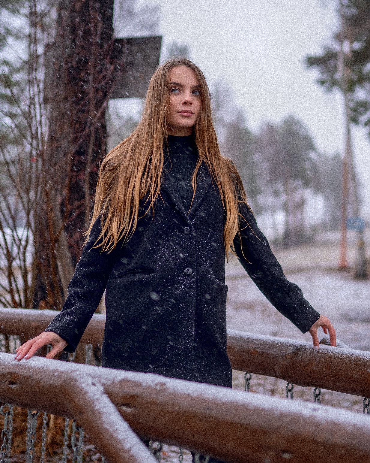 Зимняя фотосессия в лесу с первым снегом красивая девушка стоит на мостике