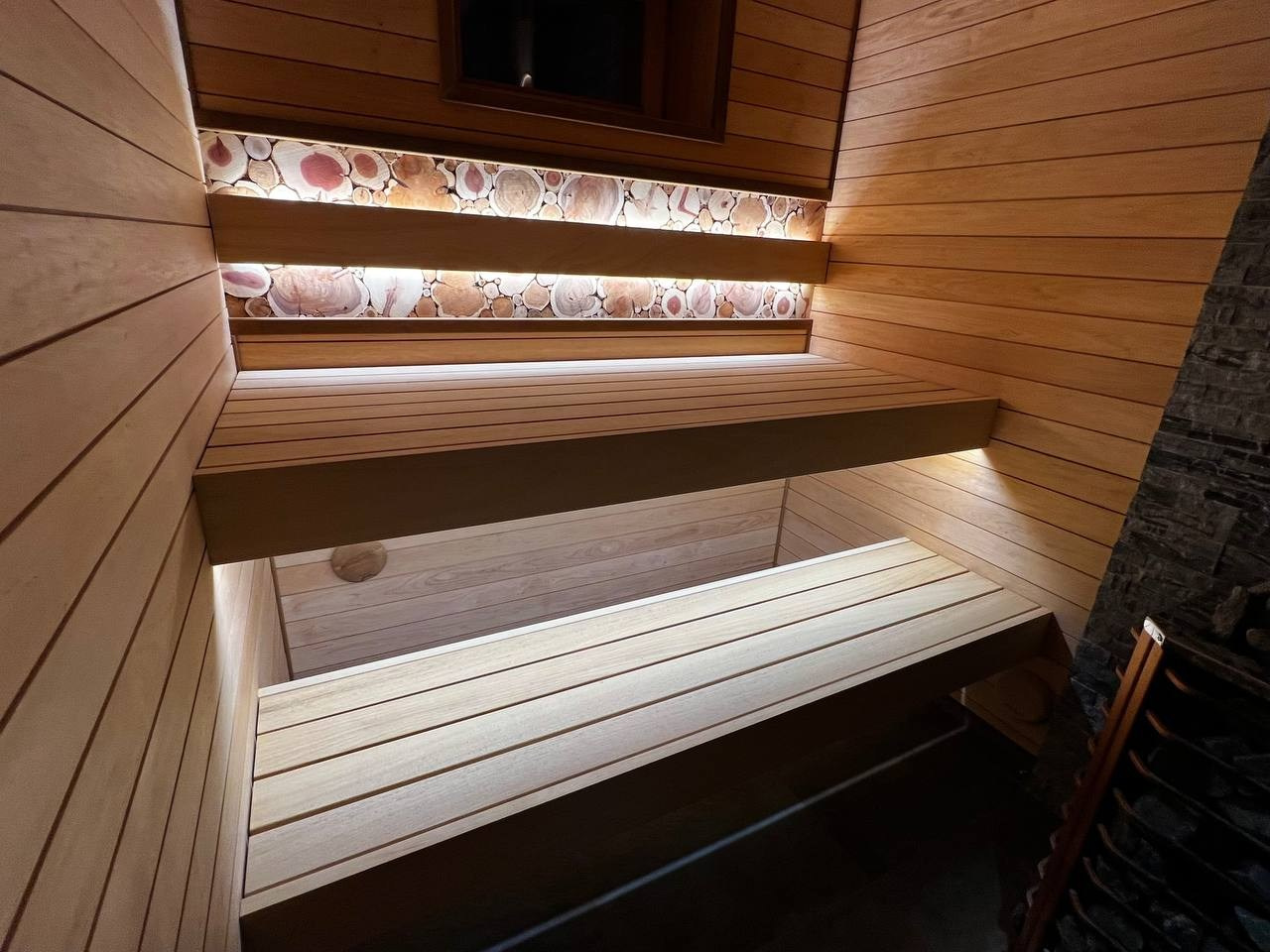 Компактная баня в Терра-Выборгском: светлая ольха в горизонтали и абаш на парящих полках визуально расширяют пространство. SaunaTopMasters