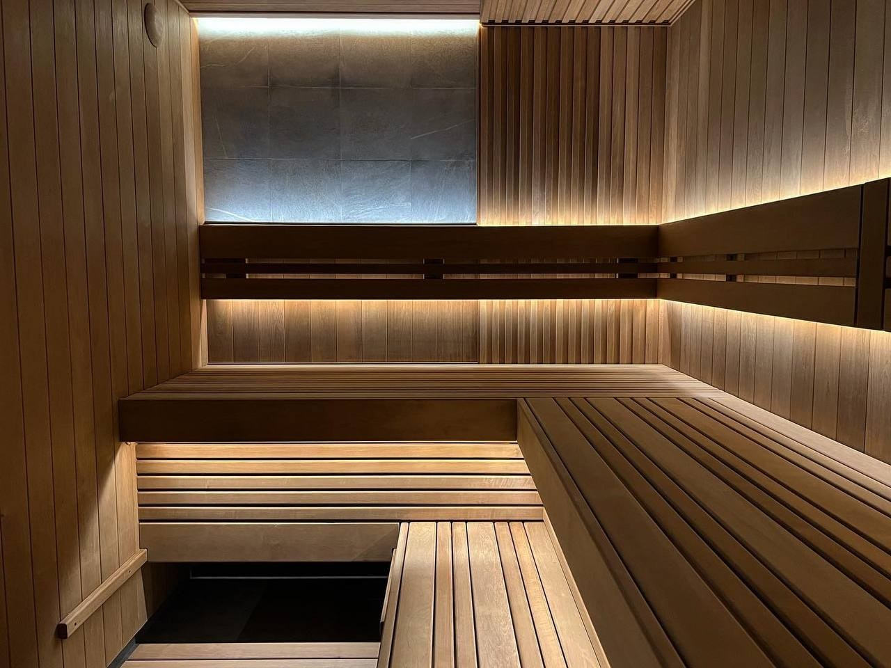Сауна в Керро из разноширокой термоольхи. Ламповый свет термостойких лент и закарнизная подсветка плитки из талькохлорита 300×300мм. SaunaTopMasters