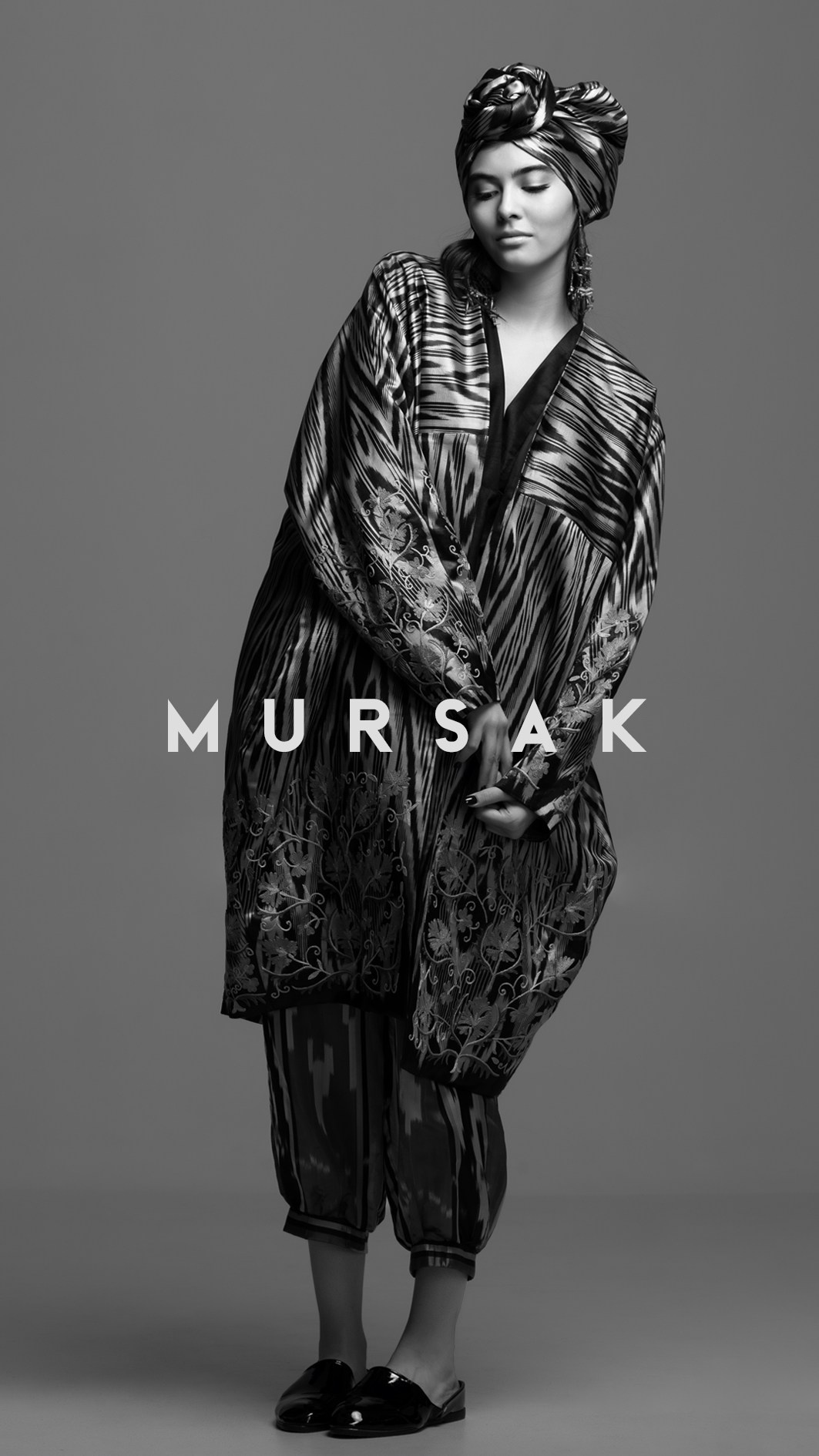 Чёрно-белый лукбук Mursak: модель в костюме с этническими узорами на тёмном студийном фоне.