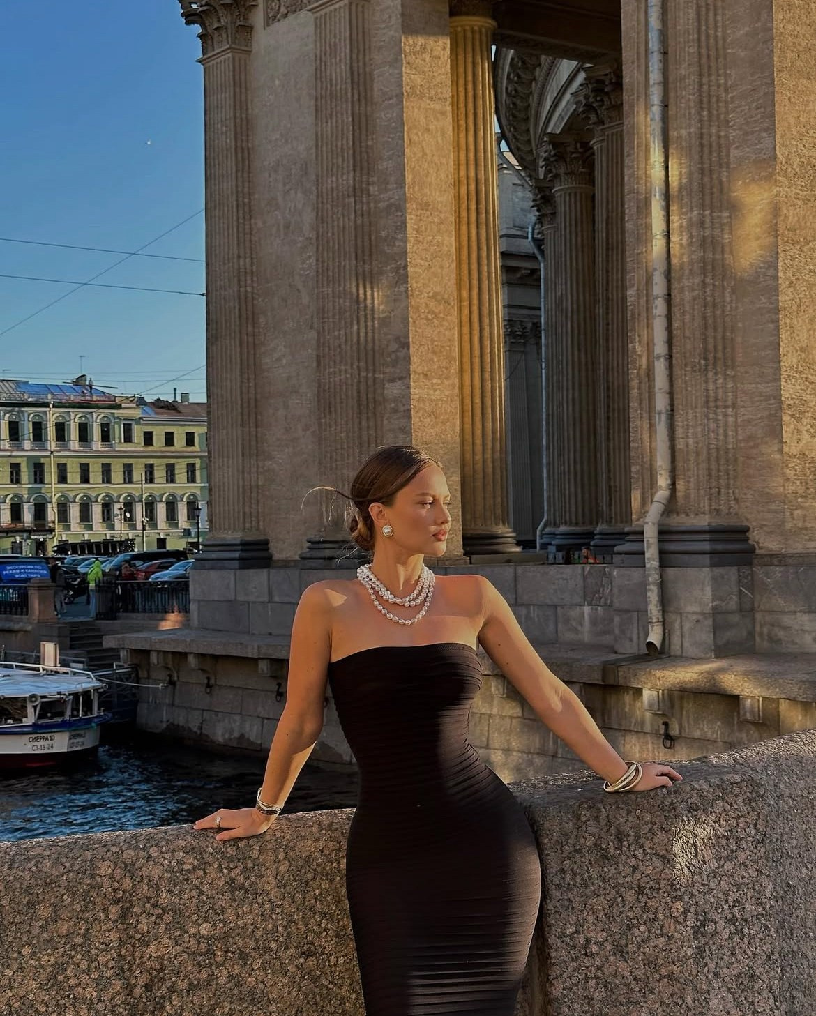 Девушка модель в черном платье стоит на фоне Казанского собора в Санкт-Петербурге
