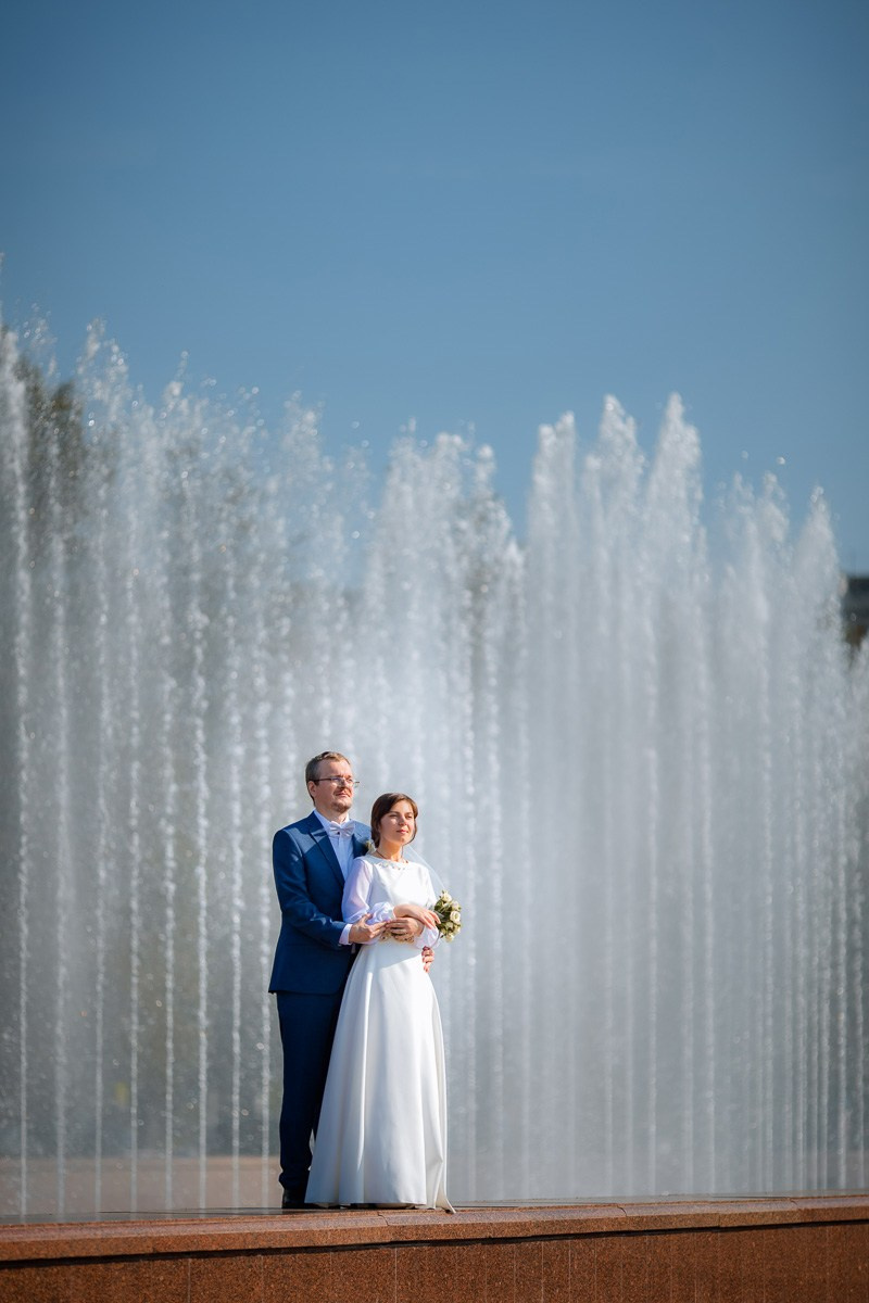 Жених и невеста стоят у фонтана у  ЗАГСа Красносельского района СПб