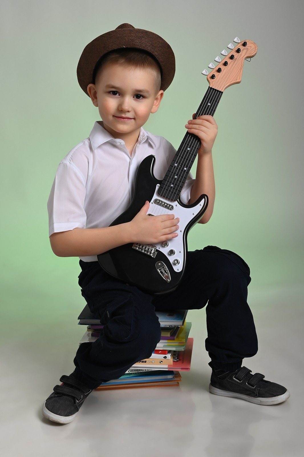 Мальчик выпускник детского сада в Вологде в белой рубашке и шляпе с гитарой в руках улыбается