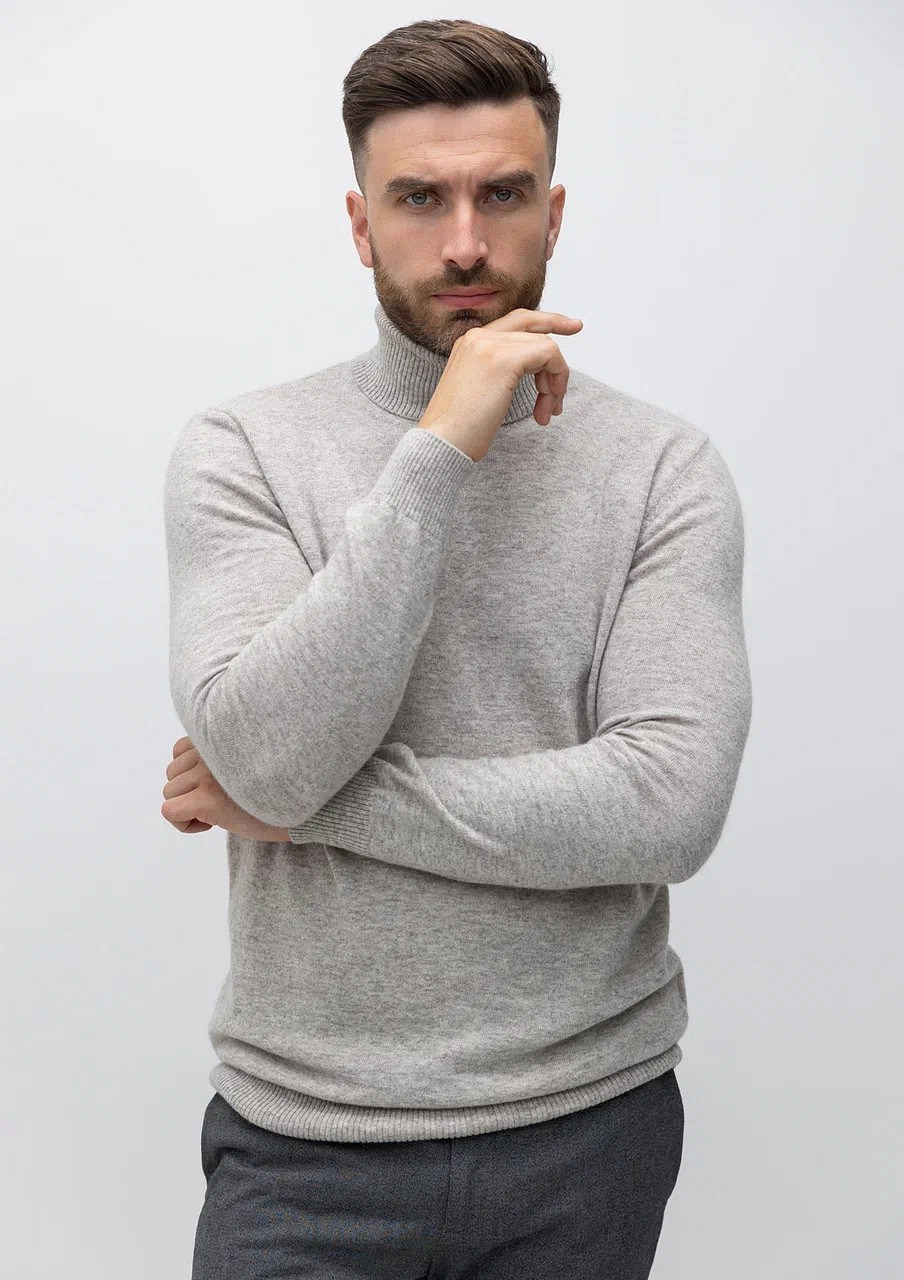 Мужчина с бородой в серой водолазке и брюках