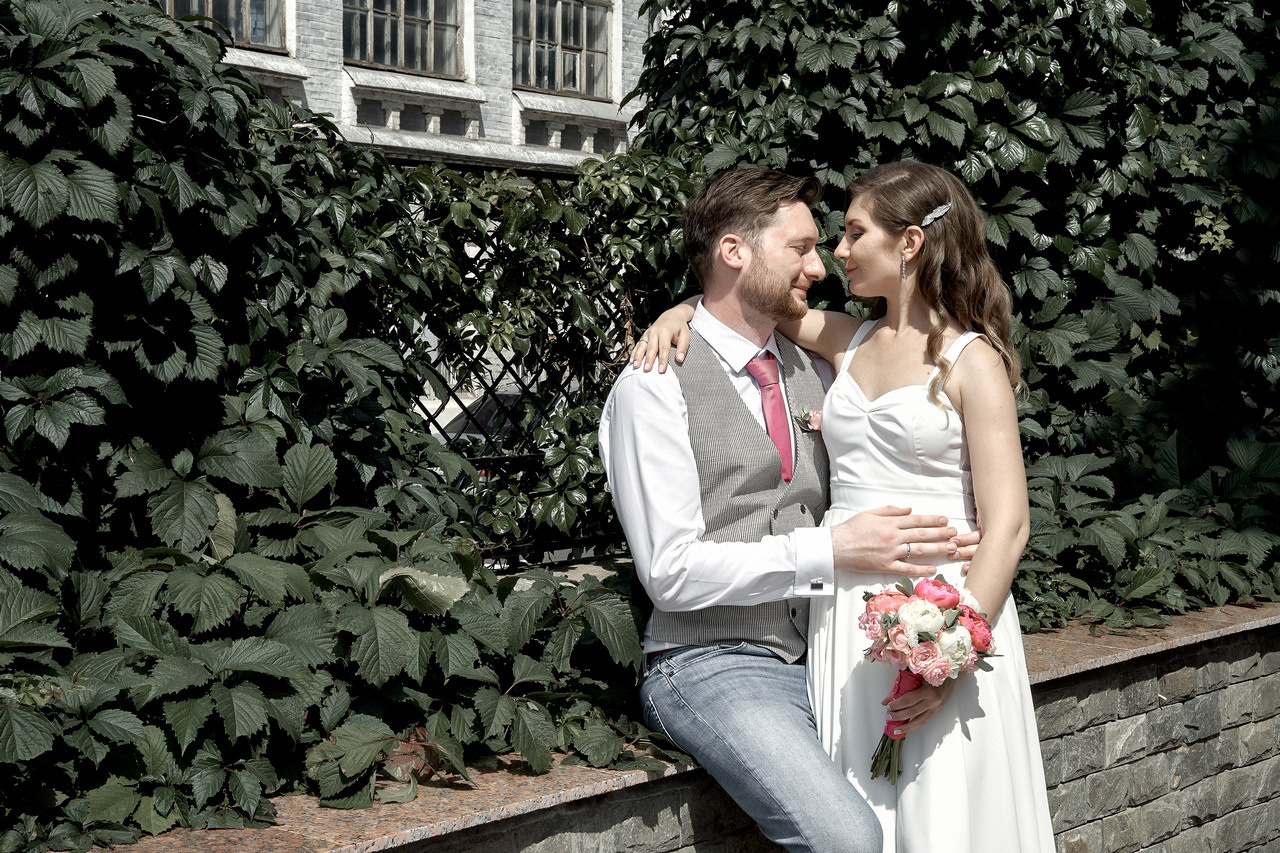 Невеста сидит на коленях жениха среди красивых зарослей кустарника Свадебная фотосъемка в Москве. Свадебный фотограф в Москве  Сергей Гаварос.