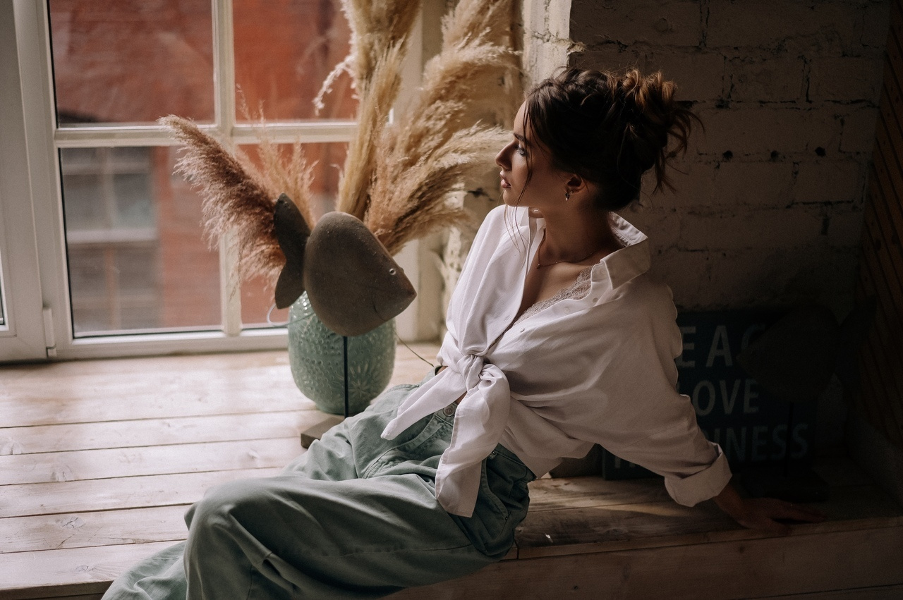 девушка в белой рубашке у окна с небрежным пучком и легким макияжем 