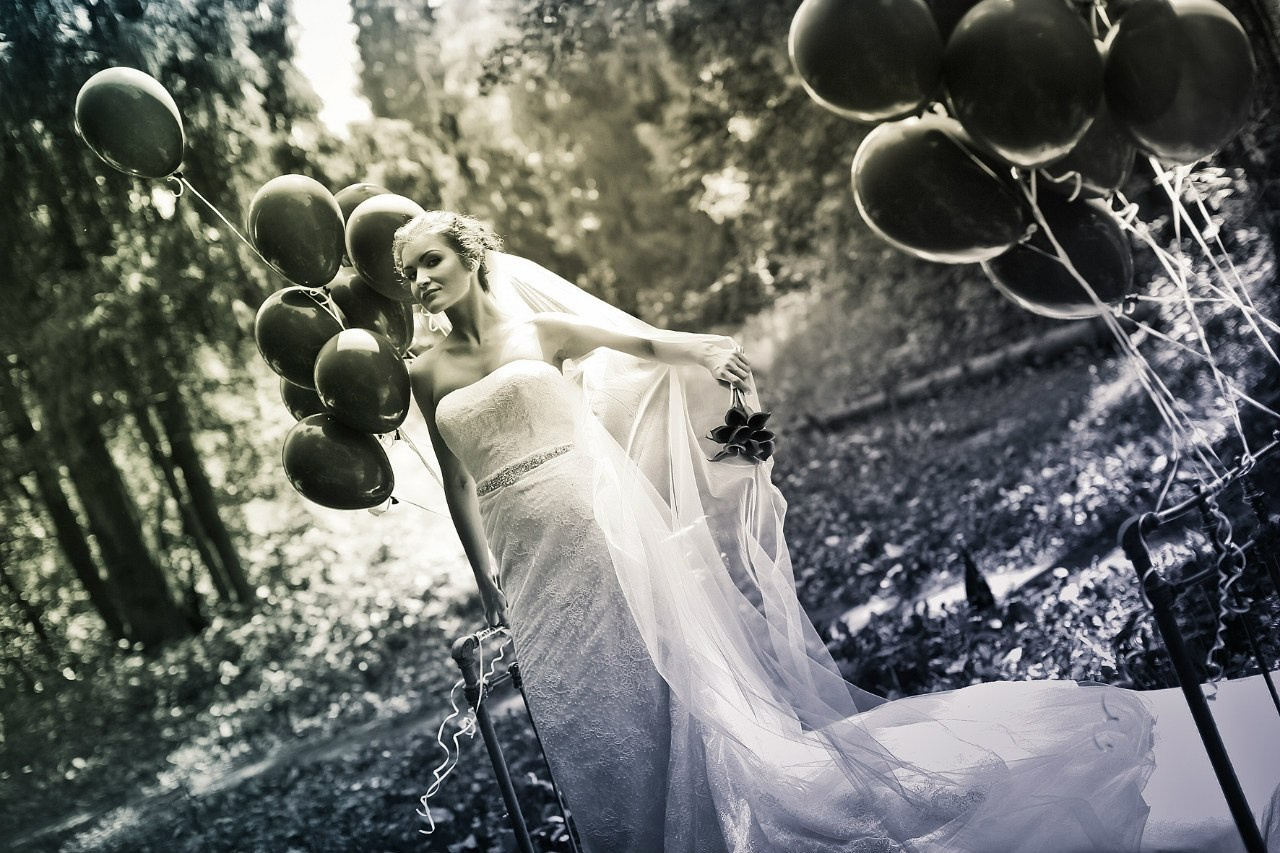 драматический портрет невесты на кровати с черными шарами в лесу