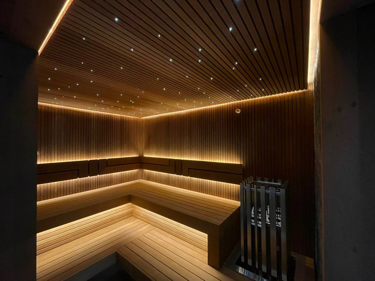 Сауна на Медном Озере из термоольхи «рейка», с тёплой подсветкой, звёздным небом и эффектным IKI Monolith на фоне итальянского камня. SaunaTopMasters