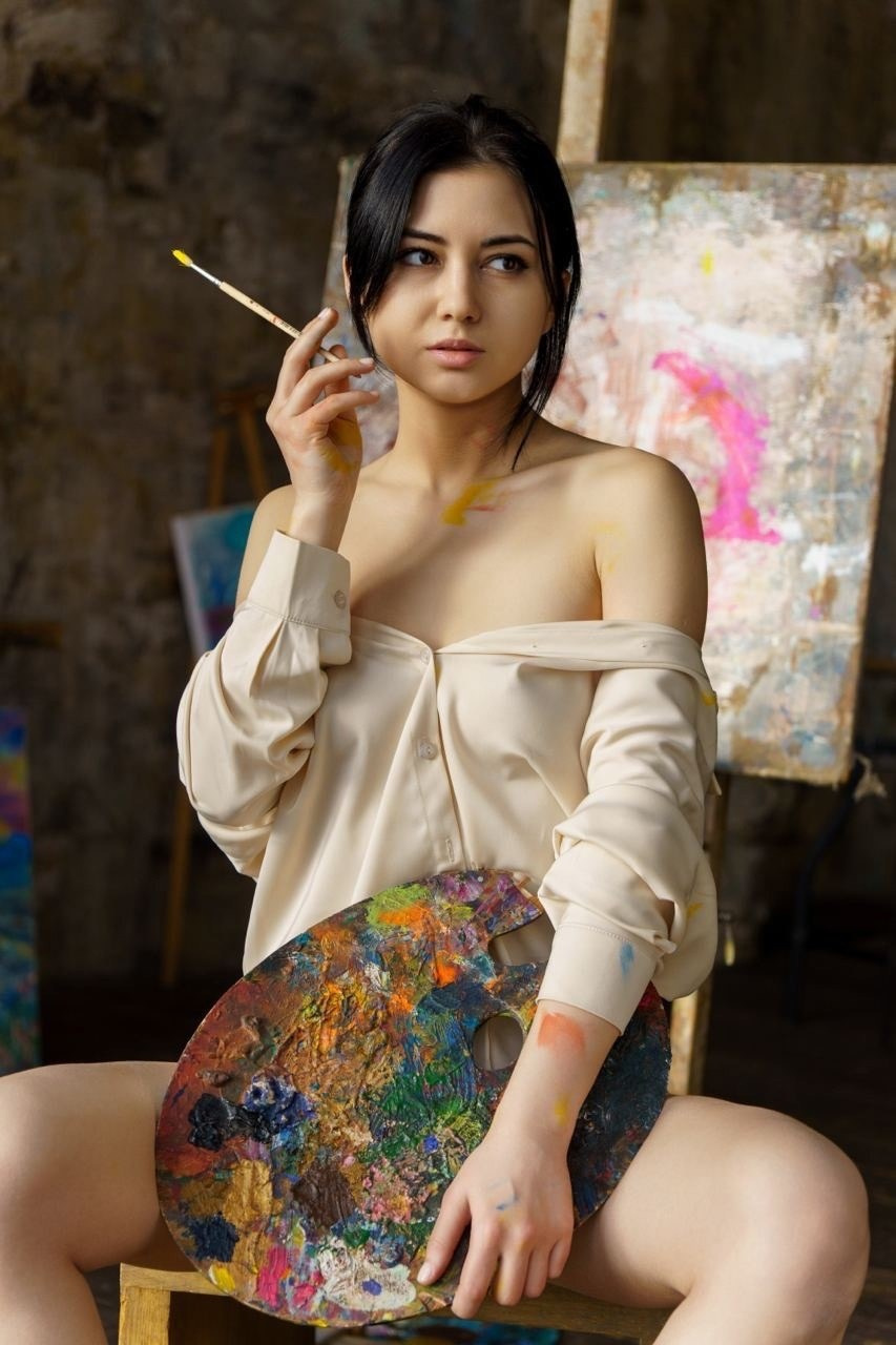 задумчивая художница с мольбертом, кисточкой  и палитрой в рубашке