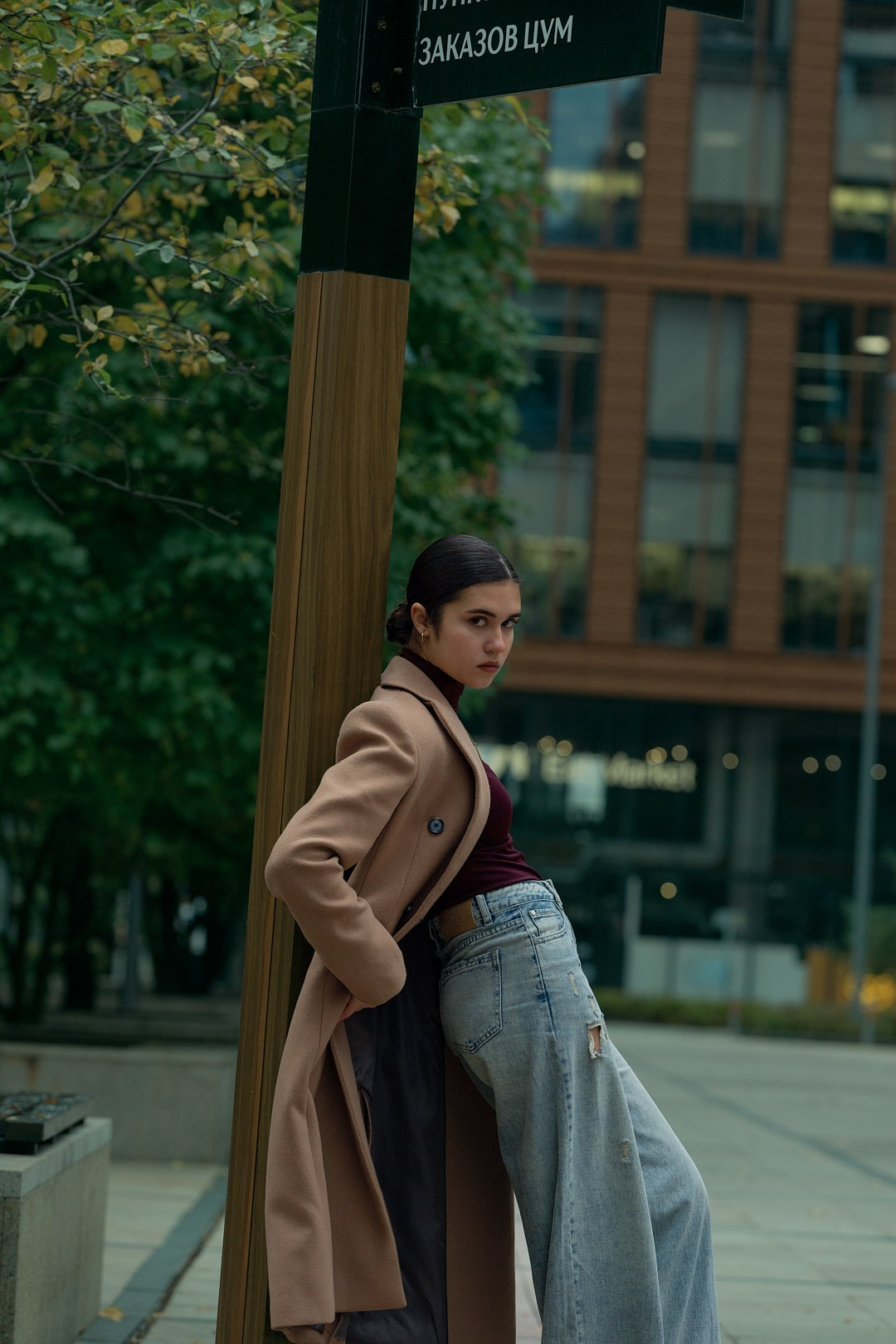Девушка в пальто позирует на фоне современной архитектуры — городской стиль