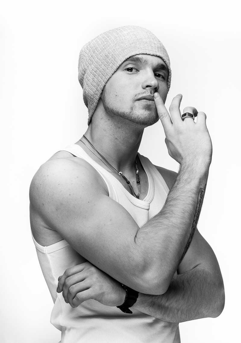 портрет мужчины в белой майке и шапке на белом фоне. Мужской портрет в фотостудии