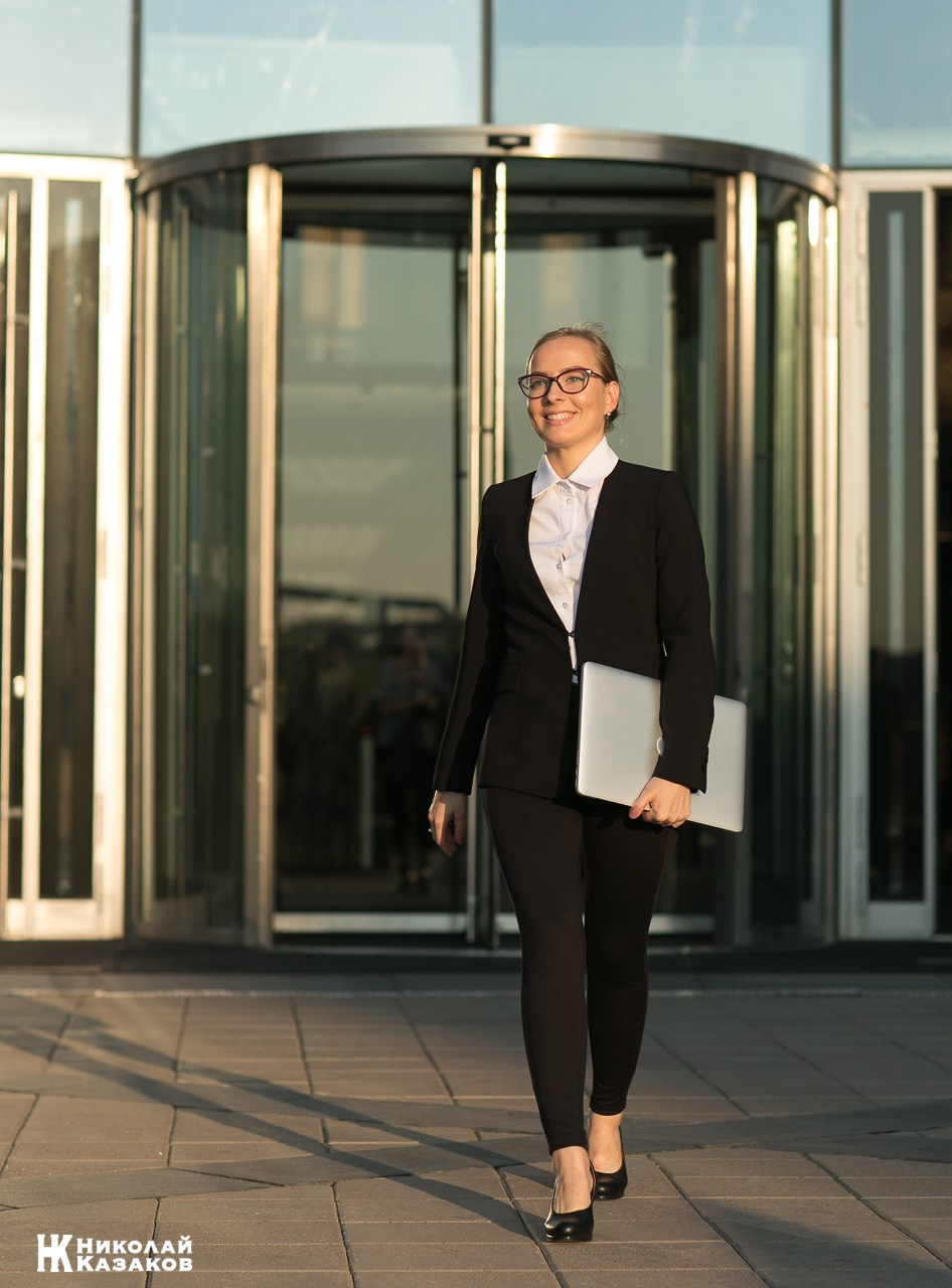 Руководитель фирмы выходит из бизнес центра с ноутбуком в руках.