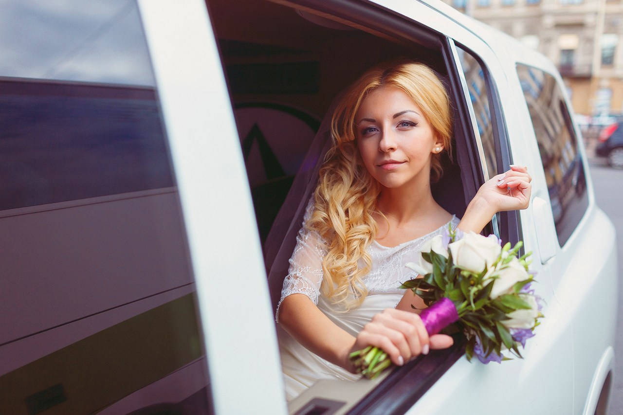 портрет блондинки невесты с белым букетом в окне лимузина