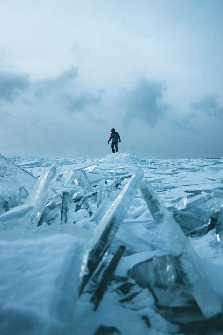 Мужчина стоит среди замерзшего льда озера Байкал