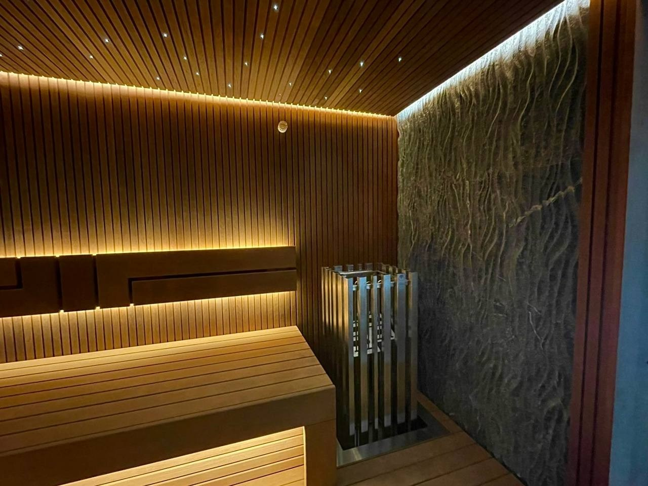 Сауна на Медном Озере из термоольхи «рейка», с тёплой подсветкой, звёздным небом и эффектным IKI Monolith на фоне итальянского камня. SaunaTopMasters